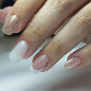 Pose gel nude avec french blanche et ongles pailletés dorés, finition brillante et forme carré arrondi.