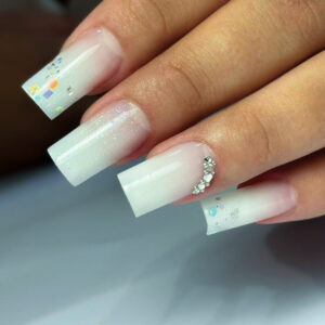 Pose gel longue forme carré avec dégradé blanc laiteux, paillettes fines et décoration strass sur ongle accent.