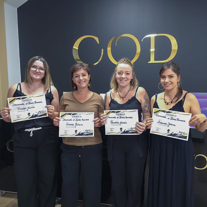 Groupe de participantes tenant leur certificat de formation devant le mur logo COD Nail System.